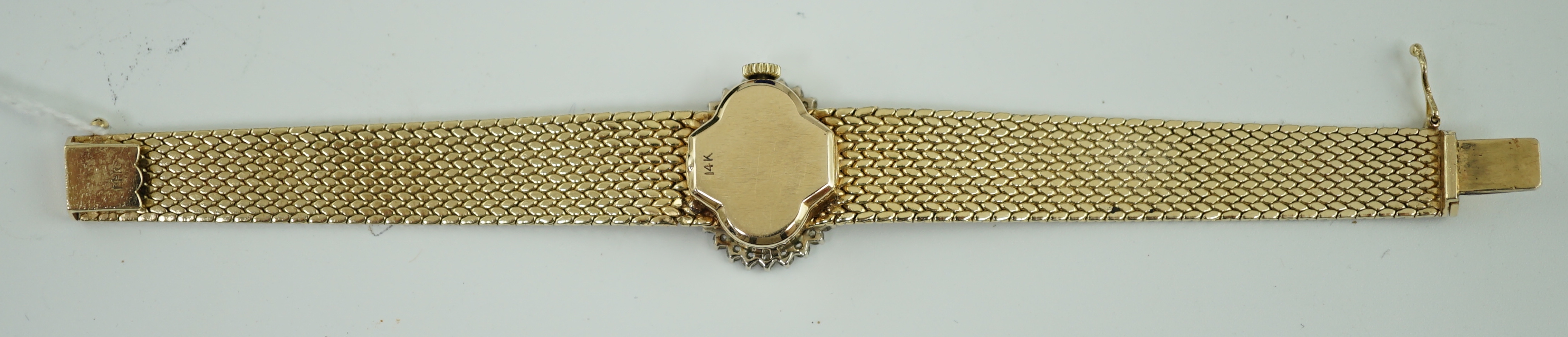 A lady's modern Swiss 14k gold and diamond set manual wind oval wrist watch, on integral 14k gold bracelet